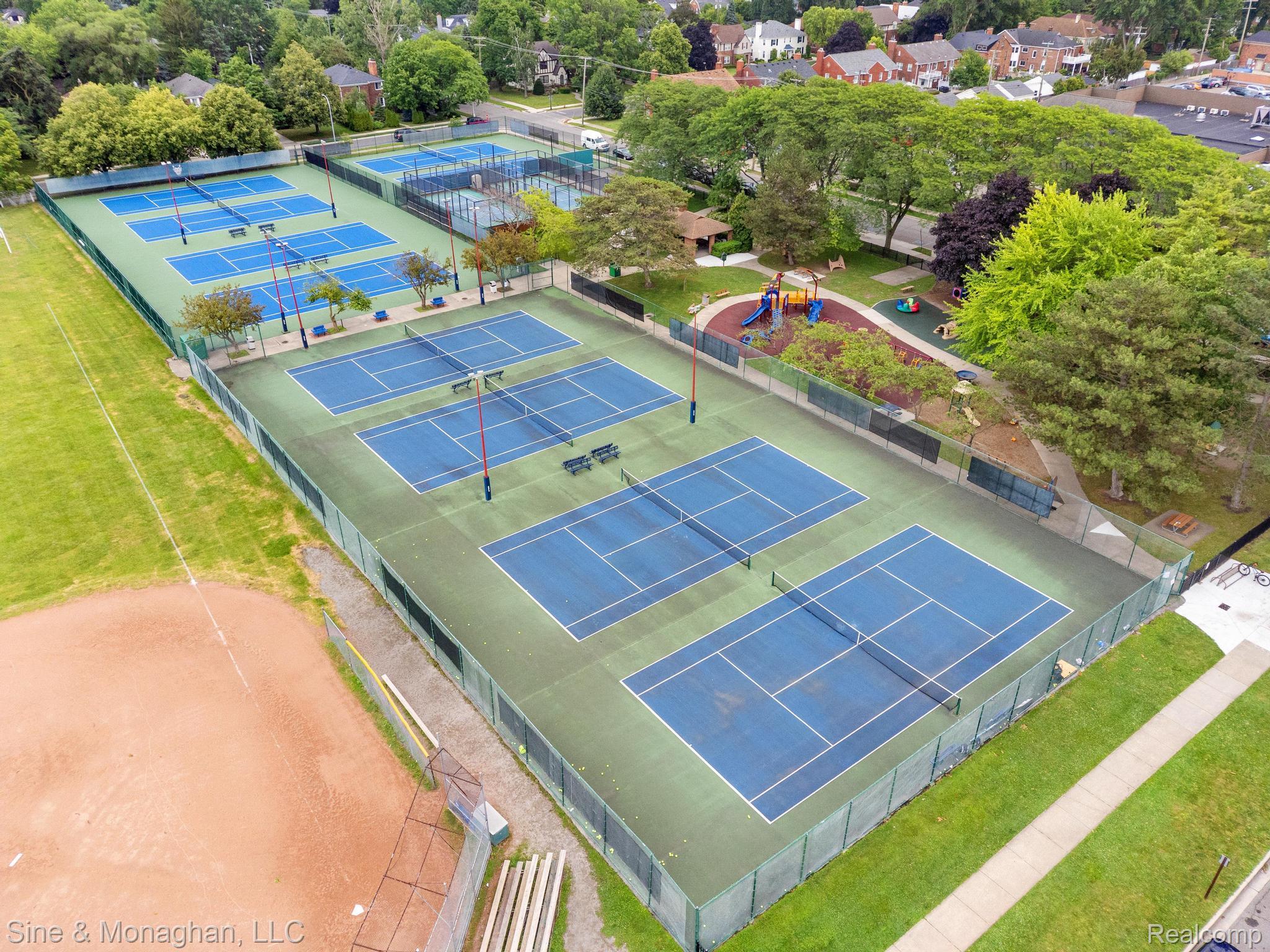 679 Neff Road Grosse Pointe, MI 48230 - Photo 52 of 78 Multi-court tennis facility with multiple blue-surfaced courts, green perimeter fencing, a nearby baseball diamond, and an adjacent playground area