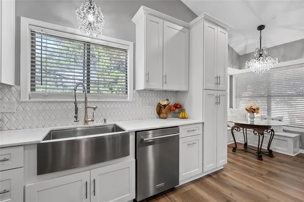 a kitchen with stainless steel appliances granite countertop a sink cabinets and wooden floor