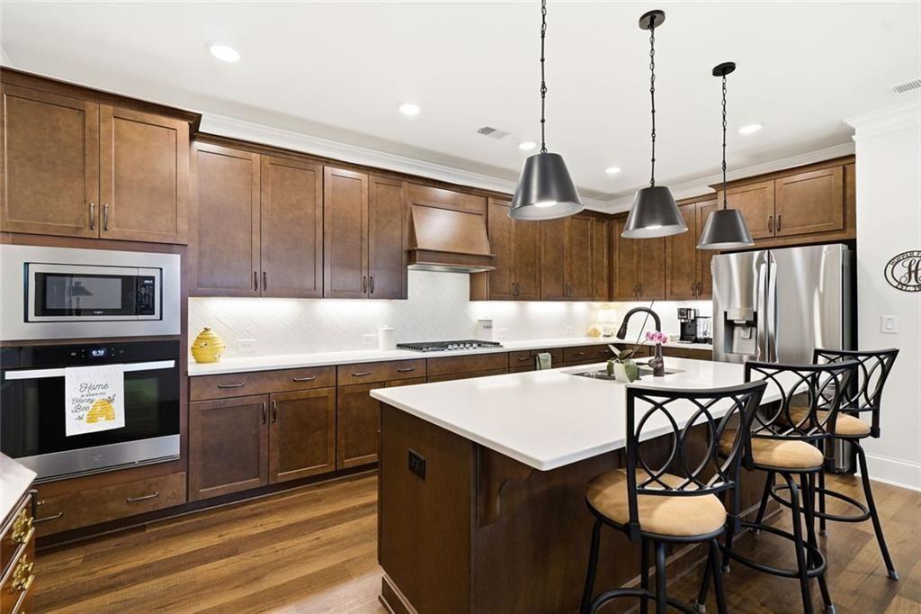 328 McQueen Way Canton, GA 30115 - Photo 21 of 66 a kitchen with stainless steel appliances granite countertop a table chairs sink and wooden cabinets