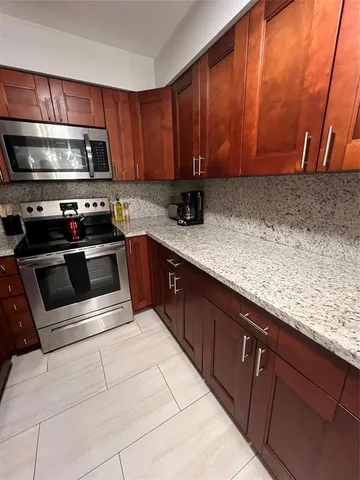a kitchen with stainless steel appliances granite countertop wooden cabinets a stove top oven a sink and dishwasher