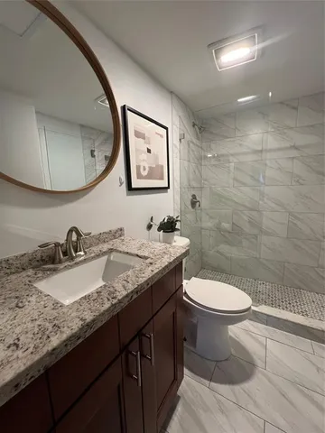 a bathroom with a granite countertop sink toilet and a mirror