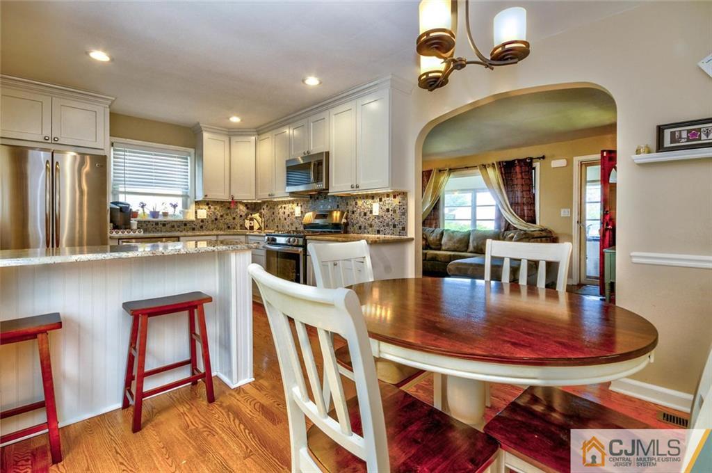 988 Clark Road North Brunswick, NJ 08902 - Photo 11 of 25 a kitchen with stainless steel appliances granite countertop a stove a refrigerator a kitchen island a dining table and chairs with wooden floor