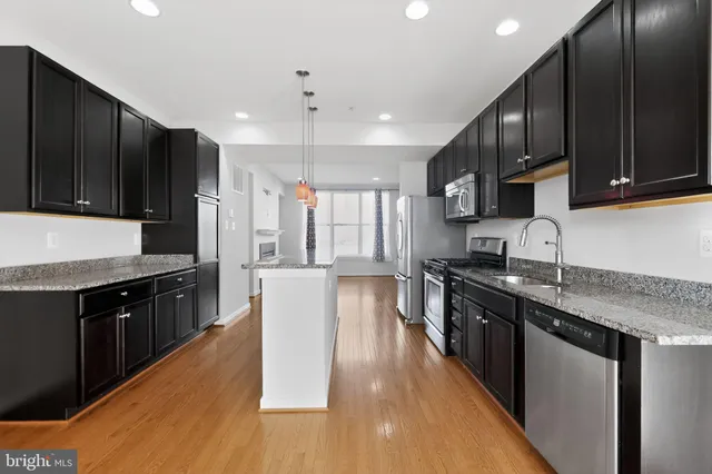 a large kitchen with stainless steel appliances wooden floors wooden cabinets a stove a sink and a oven