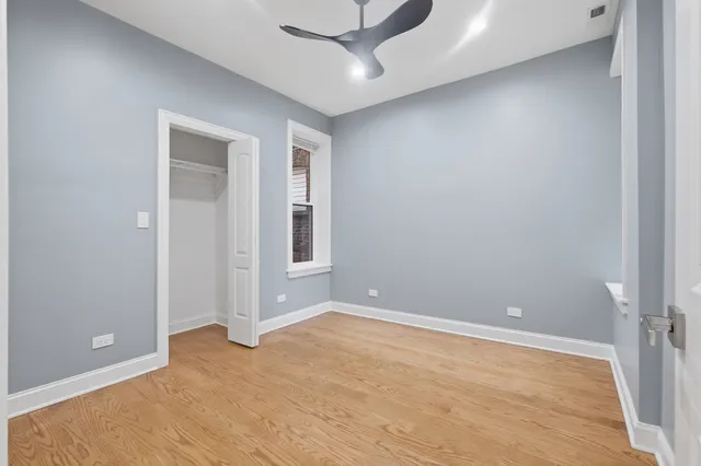 a view of an empty room with window and chandelier fan