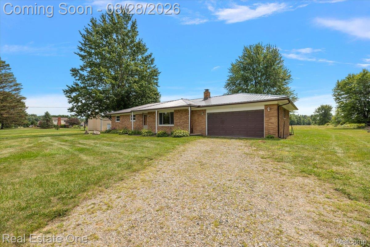 15250 34 Mile Road Armada, MI 48005 - Photo 4 of 49 Brick exterior with an attached garage, metal roof, and a gravel driveway