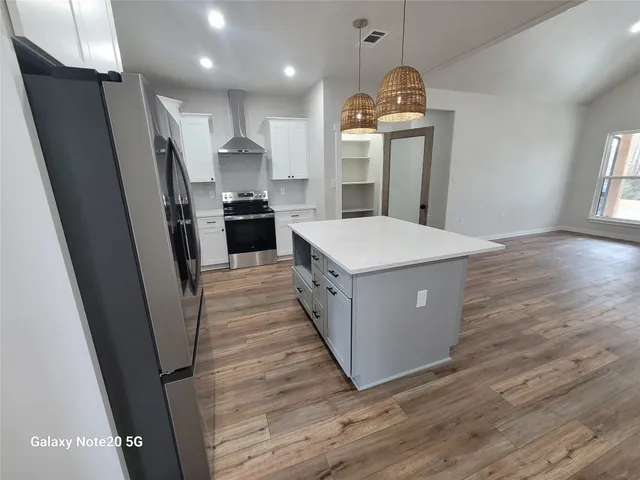 a kitchen with kitchen island a sink a stove a refrigerator and cabinets