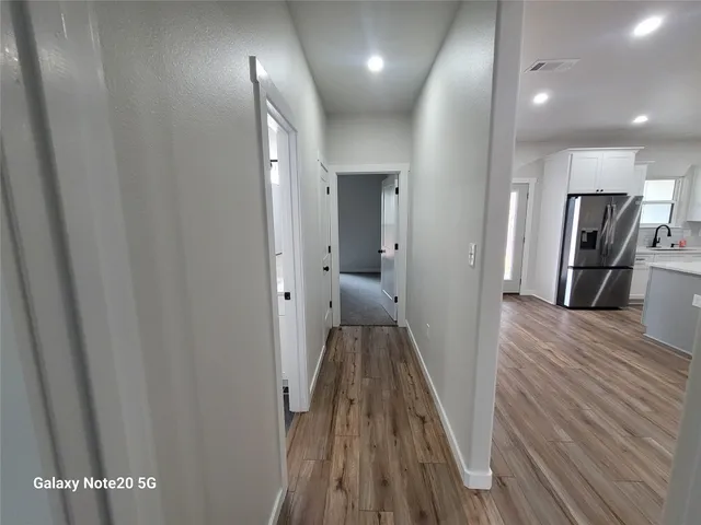 a view of a hallway with wooden floor and a bathroom