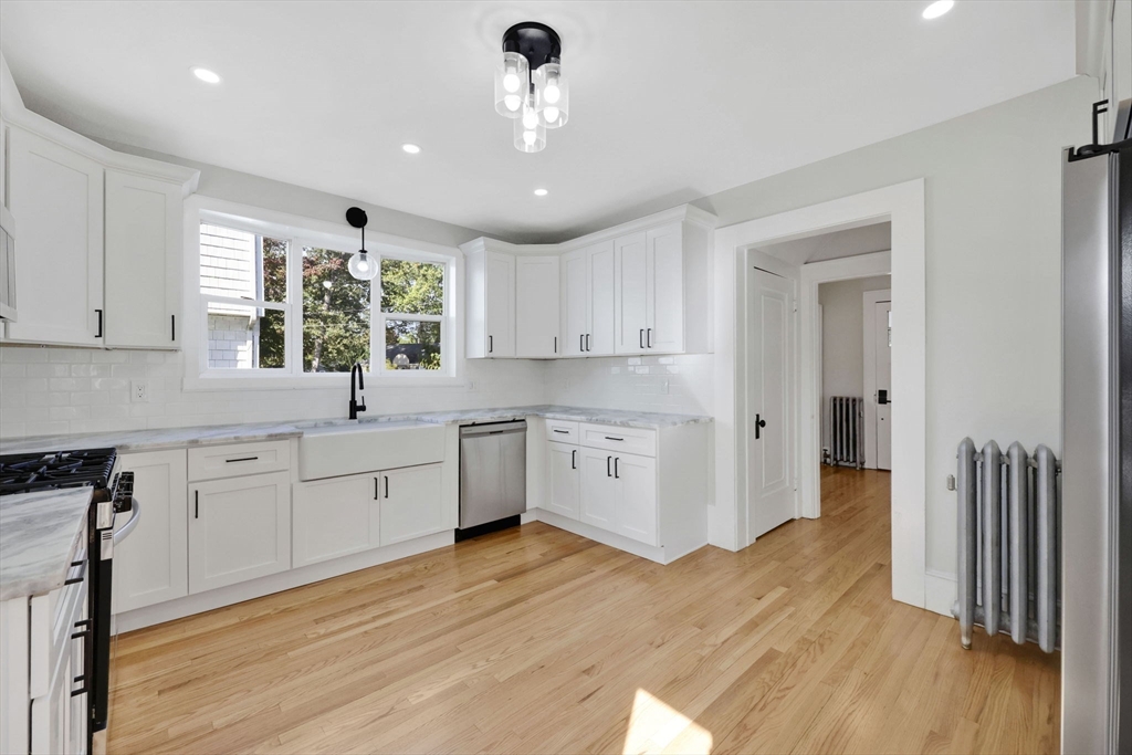 92 Grove Street West Springfield, MA 01089 - Photo 17 of 41 a large white kitchen with a window wooden floor and stainless steel appliances