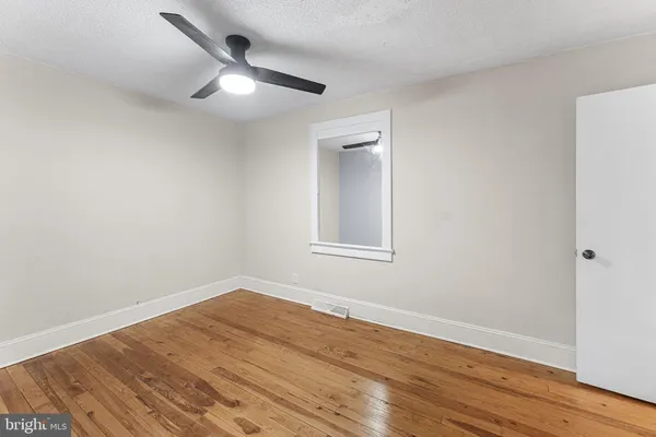 a view of a big room with wooden floor and a ceiling fan