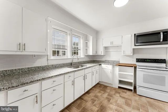 a kitchen with granite countertop white cabinets stainless steel appliances a sink and a window
