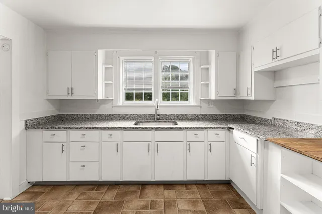 a kitchen with granite countertop white cabinets and sink