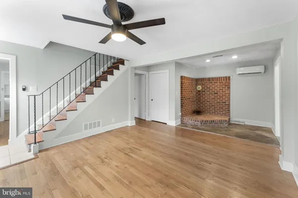 a view of an empty room with wooden floor and a ceiling fan