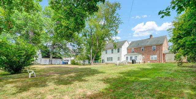a view of a house with a big yard and large trees
