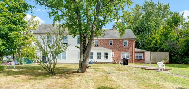 a front view of a house with a yard and large tree