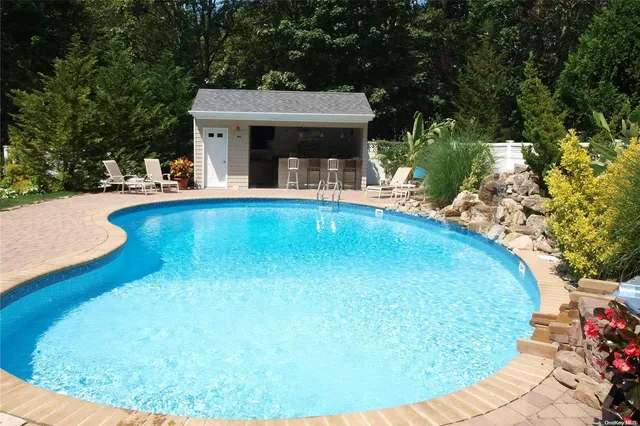 a view of a white house with a swimming pool and sitting area