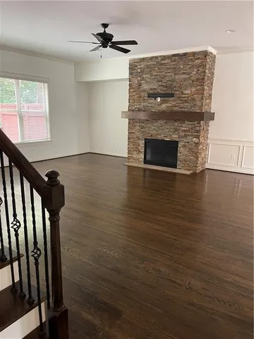 a view of an empty room with wooden floor fireplace and a window