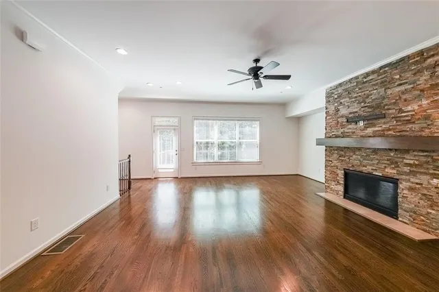an empty room with wooden floor fireplace and windows