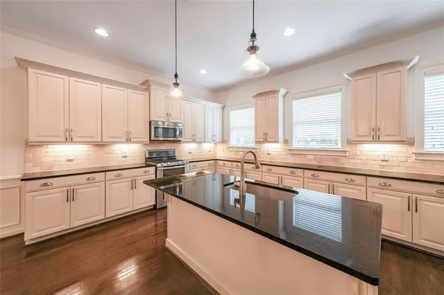a kitchen with stainless steel appliances granite countertop a sink a stove and cabinets