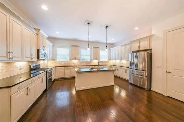 a large kitchen with a center island wooden floor stainless steel appliances and windows