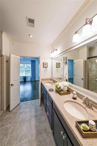 a spacious bathroom with a granite countertop double vanity sink a mirror and a shower