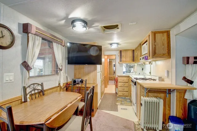 a kitchen with stainless steel appliances granite countertop a stove top oven a sink a dining table and chairs with wooden floor