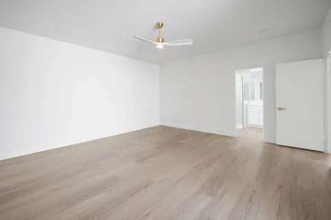 a view of empty room with wooden floor and ceiling fan