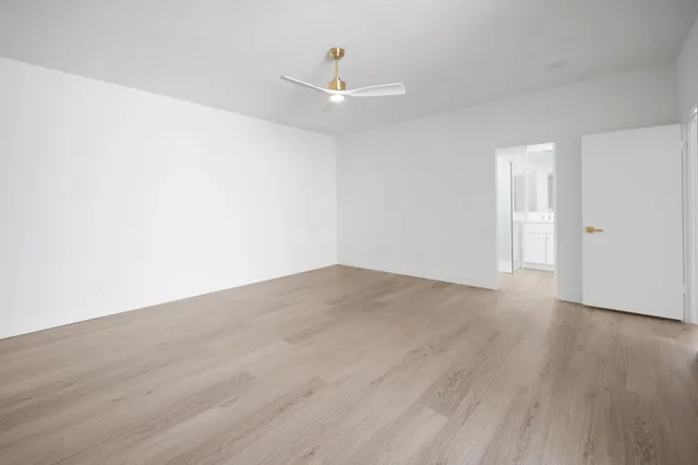 a view of empty room with wooden floor and ceiling fan
