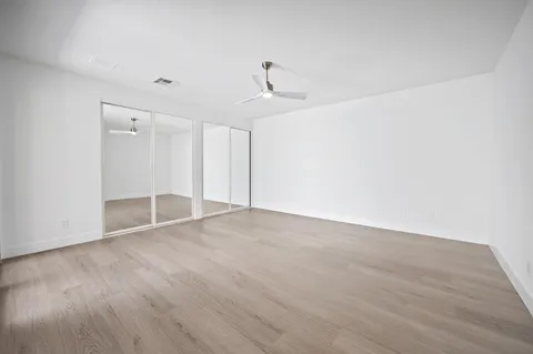 a view of empty room with wooden floor and ceiling fan