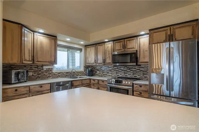a kitchen with stainless steel appliances granite countertop a refrigerator and a stove top oven