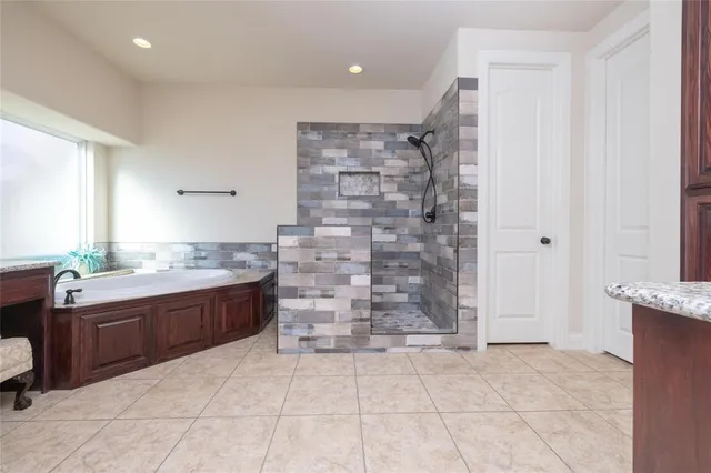 a spacious bathroom with a granite countertop sink a mirror and a bathtub