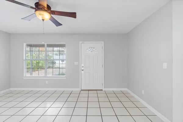 a view of an empty room and window and chandelier fan