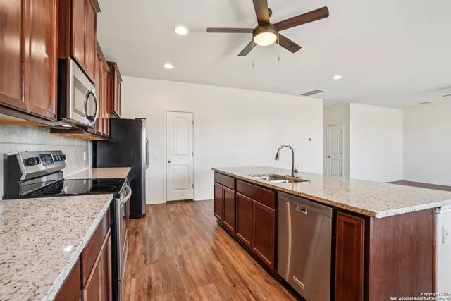 a kitchen with stainless steel appliances granite countertop a sink a stove and a wooden floors