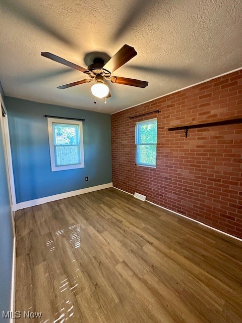 4184 Johnson Road Barberton, OH 44203 - Photo 9 of 25 Unfurnished bedroom featuring brick wall, a textured ceiling, dark wood finished floors, ceiling fan, and a closet
