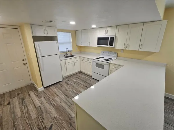 a kitchen with a sink a refrigerator a microwave and cabinets