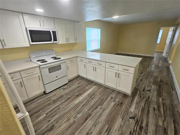 a white kitchen with sink a stove and microwave