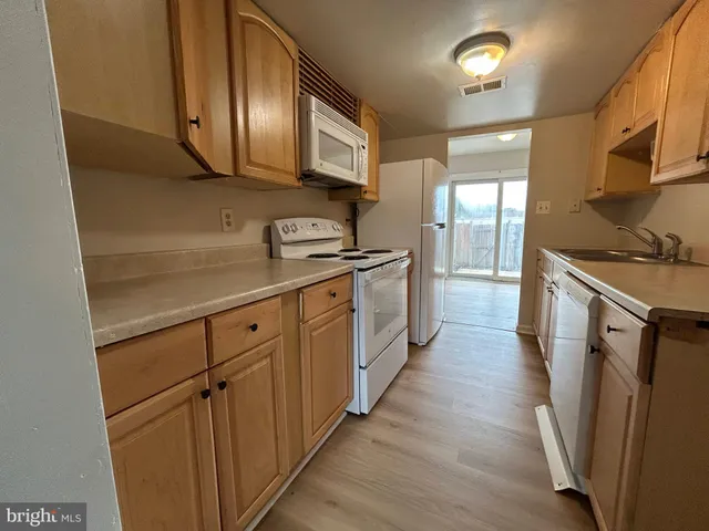 a kitchen with cabinets stainless steel appliances a sink and wooden floor