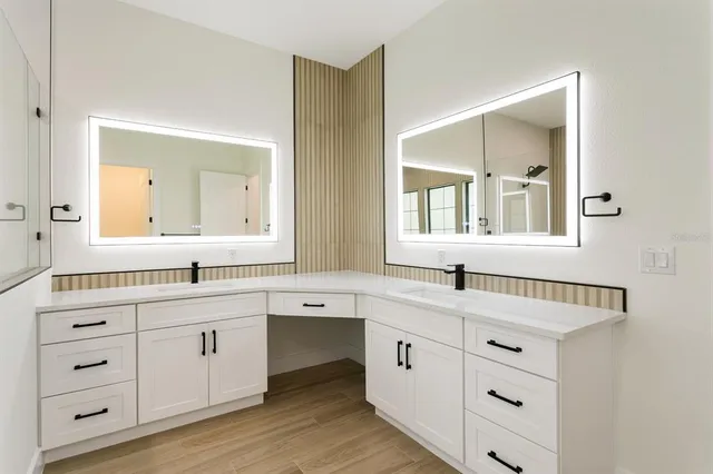 a bathroom with a double vanity sink and mirror with bathtub