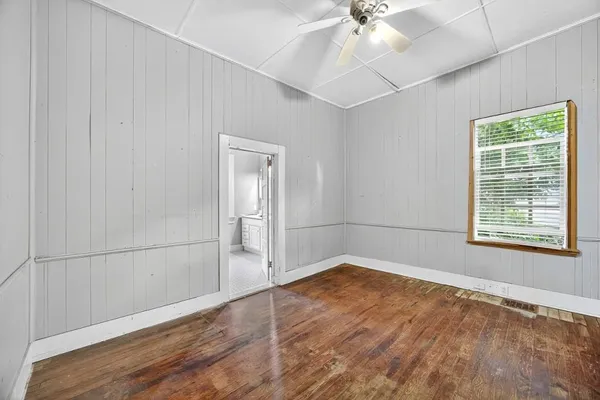 a view of an empty room with wooden floor and a window