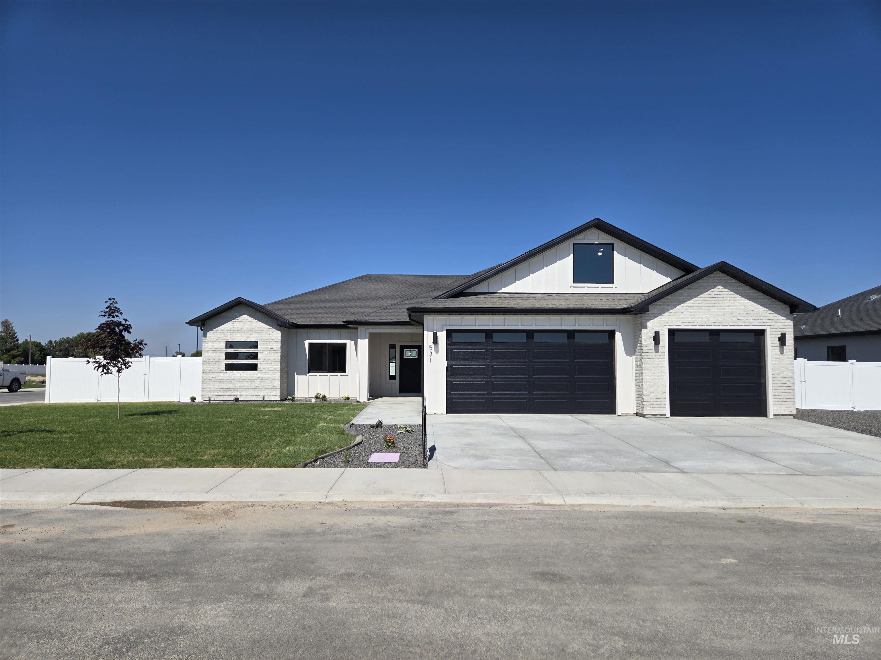 View of front facade with a garage, concrete driveway, brick siding, board and batten siding, and roof with shingles