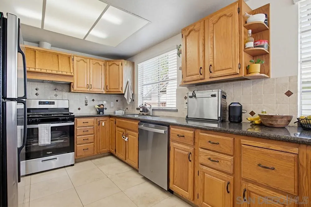431 Nantucket Escondido, CA 92027 - Photo 15 of 30 a kitchen with granite countertop white cabinets stainless steel appliances a sink and a window