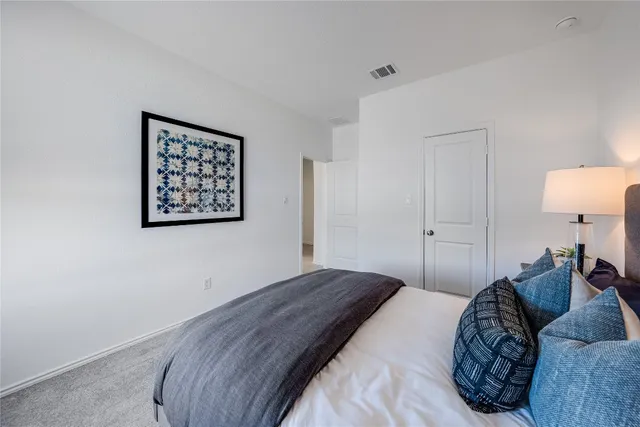 a bedroom with a bed and a lamp on dresser
