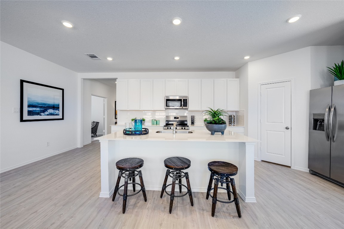 104 Stumpy Street San Marcos, TX 78666 - Photo 2 of 23 a kitchen with stainless steel appliances a dining table chairs refrigerator and wooden floor