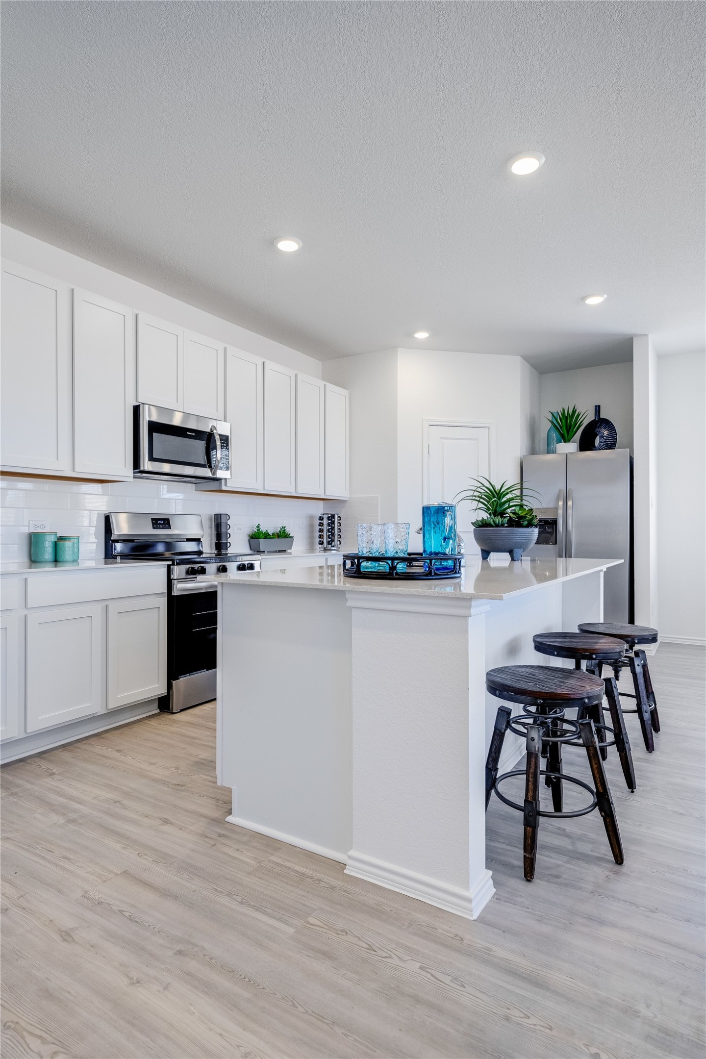 104 Stumpy Street San Marcos, TX 78666 - Photo 5 of 23 Kitchen with a center island, stainless steel appliances, backsplash, light wood-type flooring, and recessed lighting