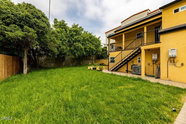 a view of an house with backyard and a tree