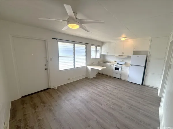 a kitchen with stainless steel appliances granite countertop a refrigerator a sink dishwasher a stove and white countertops with wooden floor