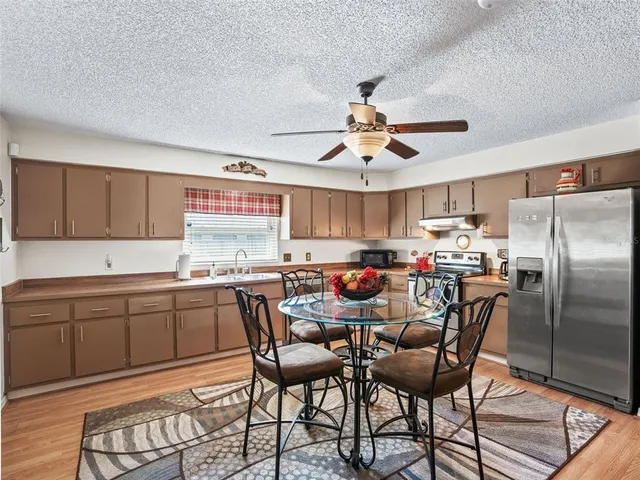 a kitchen with stainless steel appliances a table chairs and a refrigerator