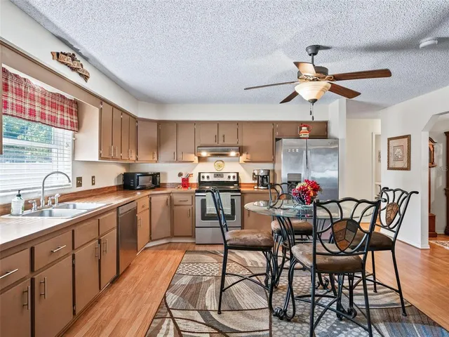 a kitchen with stainless steel appliances a table and chairs in it