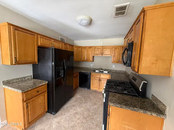 a kitchen with granite countertop stainless steel appliances a refrigerator stove top oven and sink