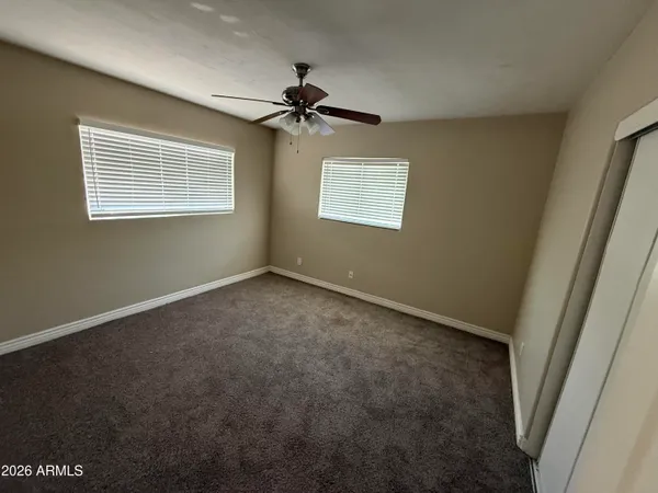 an empty room with windows and fan