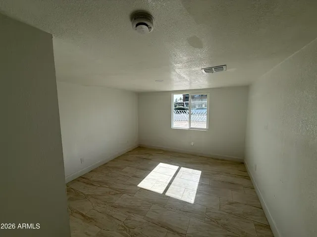 an empty room with wooden floor and bathroom view